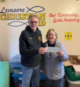 Kings Lions Club's Ray Etchegoin awards a $1,000 check to Karen Christensen of Lemoore Christian Aid.